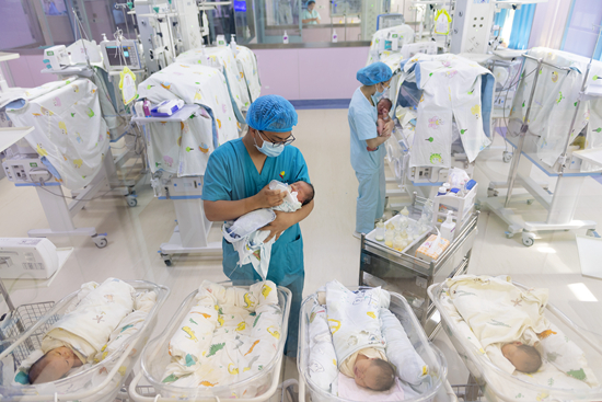 5月10日,李卓祥(左)为病房里的新生患儿喂奶