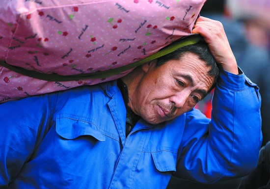 2月3日,北京站,一位大爷扛着行李进站.视觉中国供图